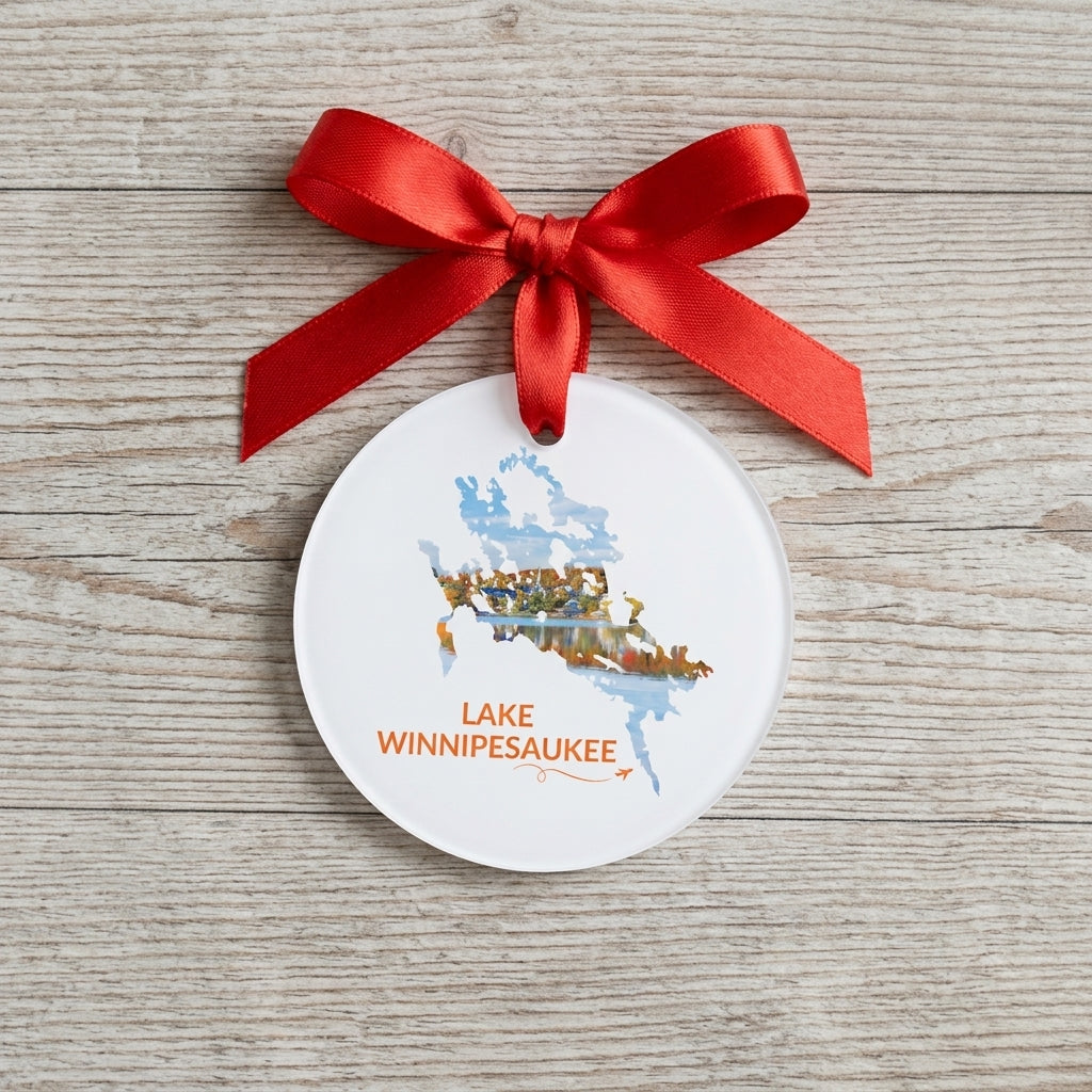 White Lake Winnipesaukee ornament with red ribbon on a wood surface, featuring Meredith in fall foliage inside the lake outline and orange lettering