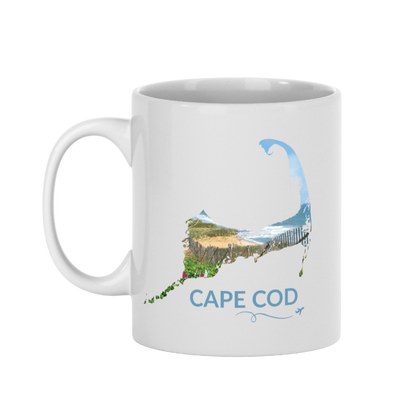 White 11 oz Cape Cod mug featuring a beach scene with sand fence, dunes, ocean and beach roses inside the Cape Cod outline, blue Cape Cod lettering, and a small airplane with swirl