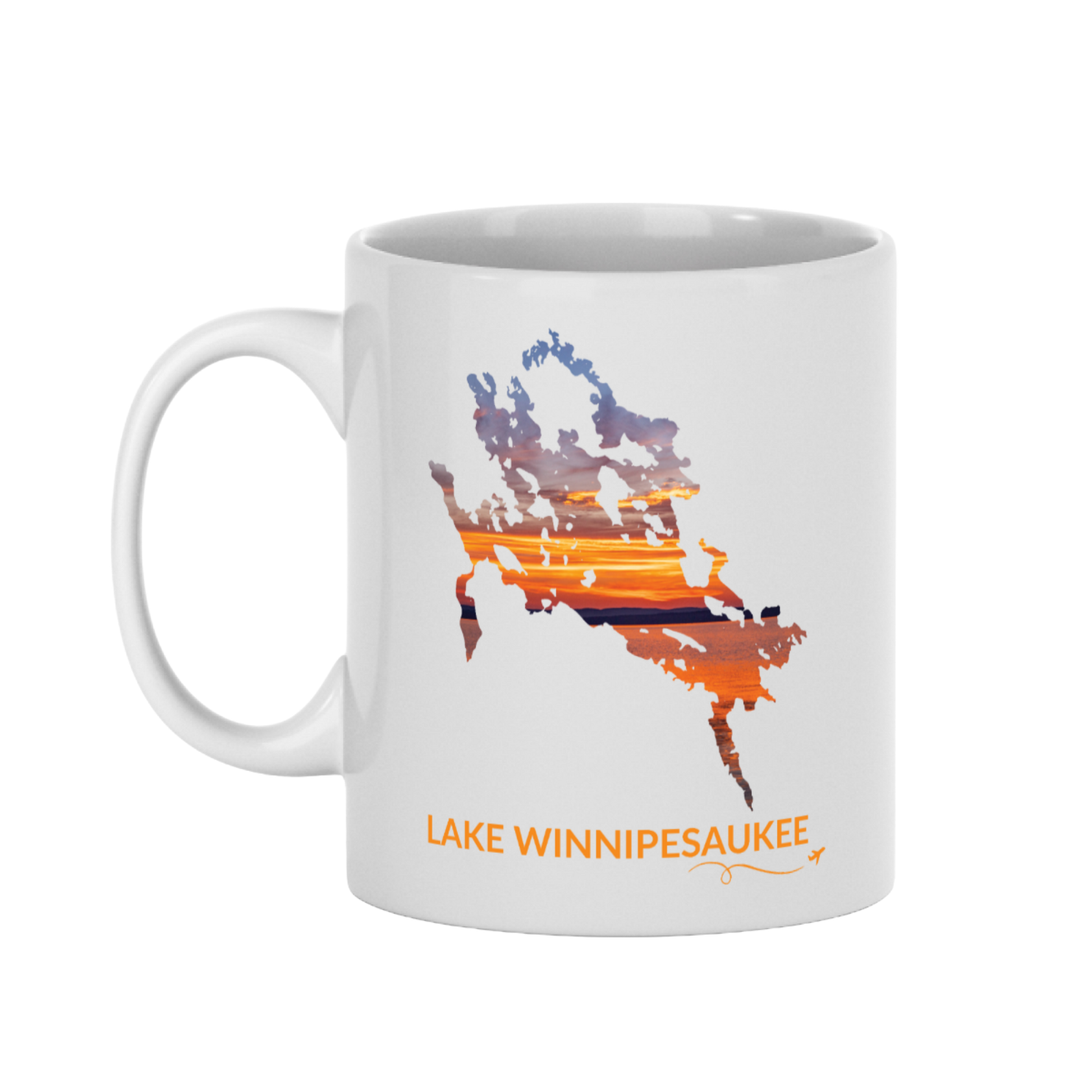 White 11 oz ceramic mug featuring a hand-drawn outline of Lake Winnipesaukee filled with a photograph of an orange and gold sunset captured on the lake. The words “Lake Winnipesaukee” appear below the artwork with a small airplane icon and looping flight path.