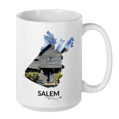 White 15 oz Salem, Massachusetts mug featuring a hand-drawn Salem outline filled with a real photograph of the Witch House, SALEM lettering underneath, and a plane with a swirl line.