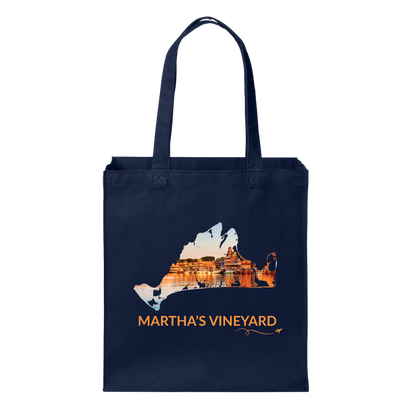 Navy cotton canvas tote bag featuring a hand-drawn Martha's Vineyard outline showcasing Oak Bluffs Harbor at sunset with glowing waterfront buildings reflected in the harbor. The words "Martha's Vineyard" appear below the artwork with a small airplane icon and looping flight path.