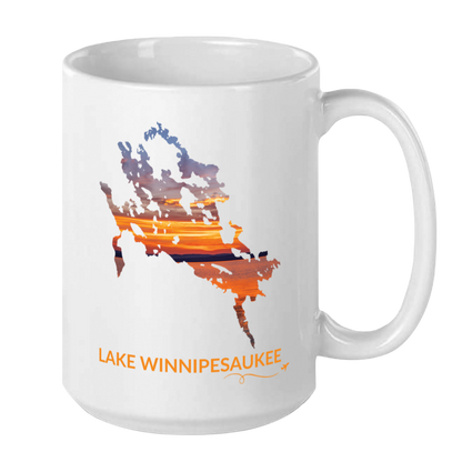 White 15 oz ceramic mug featuring a hand-drawn outline of Lake Winnipesaukee filled with a photograph of a colorful sunset captured on the lake. The words “Lake Winnipesaukee” appear below the artwork with a small airplane icon and looping flight path.