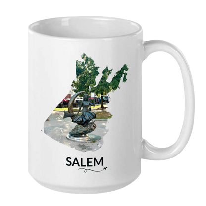 White 15 oz Salem mug featuring the Bewitched Sculpture inside the Salem outline, Salem lettering, and a small plane with a swirly line.