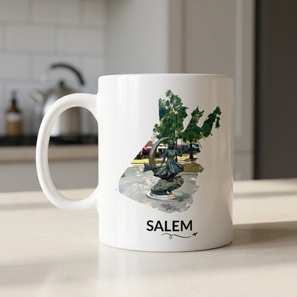 White Salem mug featuring the Bewitched Sculpture inside the Salem outline, displayed on a kitchen counter with Salem lettering and a small airplane with swirly line.