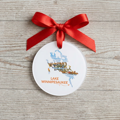 White Lake Winnipesaukee ornament with red ribbon on a wood surface, featuring Meredith in fall foliage inside the lake outline and orange lettering