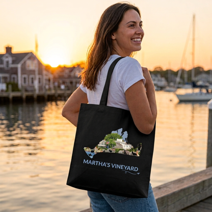 Woman carrying a black cotton canvas tote bag featuring a hand-drawn Martha's Vineyard outline filled with Edgartown Harbor and historic waterfront homes. The words "Martha's Vineyard" appear below the artwork with a small airplane icon and looping flight path.